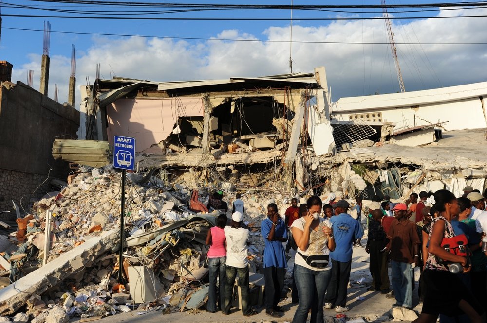 Haitians stand amongst the Port-au-Prince ruins.