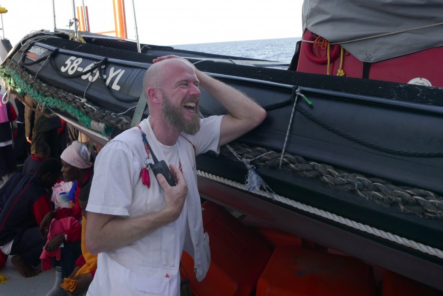 MSF nurse Steffen Bürk takes a moment to watch people celebrate the news that they will be disembarking in Italy.