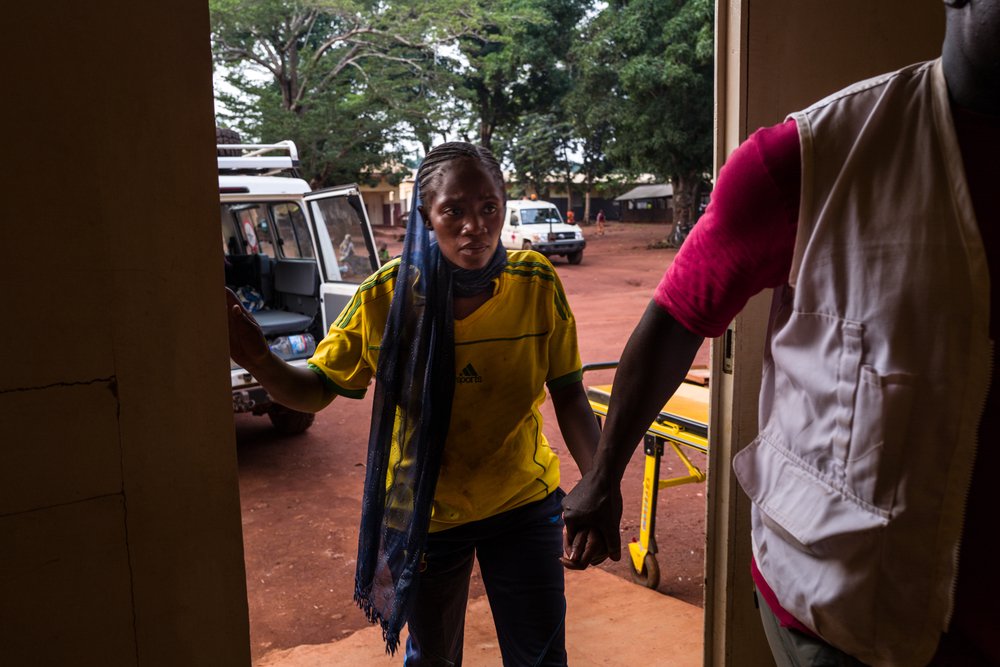 Veronique Napese enters through the emergency door of the Bangassou hospital, accompanied by the nurse Pelé Hubert Kotho-Gawe