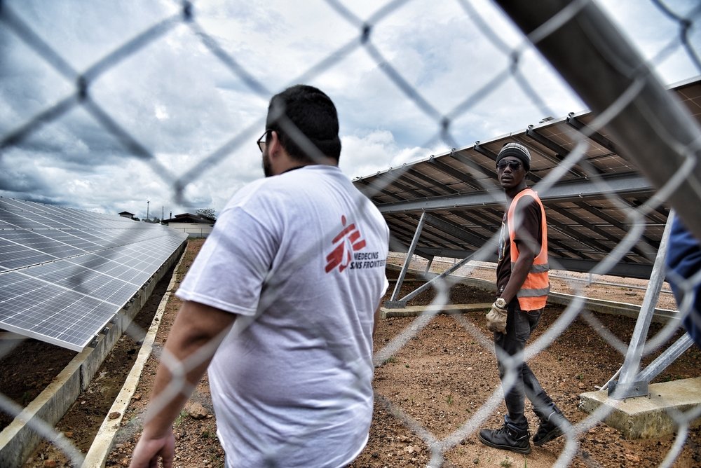 MSF supply manager Gerardo Rivera and logistics supervisor Mohammed Korma check the solar panels that partially power Hangha hospital in Kenema district. The MSF plans to run the hospital fully with clean energy in the future.