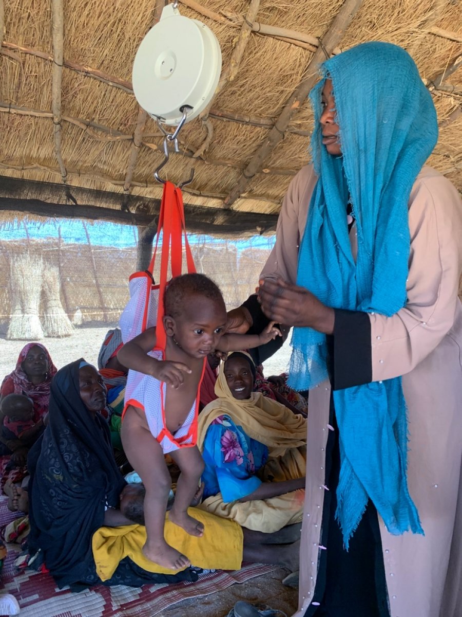 MSF medical staff weighing a child for malnutrition in MSF clinic, Dilli village, Jebel Marra Mountains, Darfur Region. Sudan