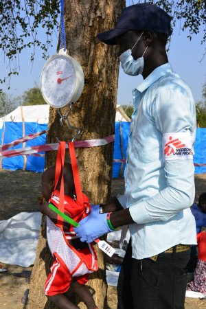 An MSF nurse aid weighs a baby before a medical consultation in the MSF mobile clinic set-up in Riang, Jonglei State.