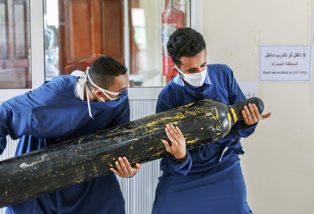 Two workers at Al-Sahul COVID-19 centre, Yemen are trying to carry the oxygen bottle in order to transfer it to inside the ICU,  provide oxygen for COVID-19 patients it&#039;s  a long and exhausting job. July 2020.