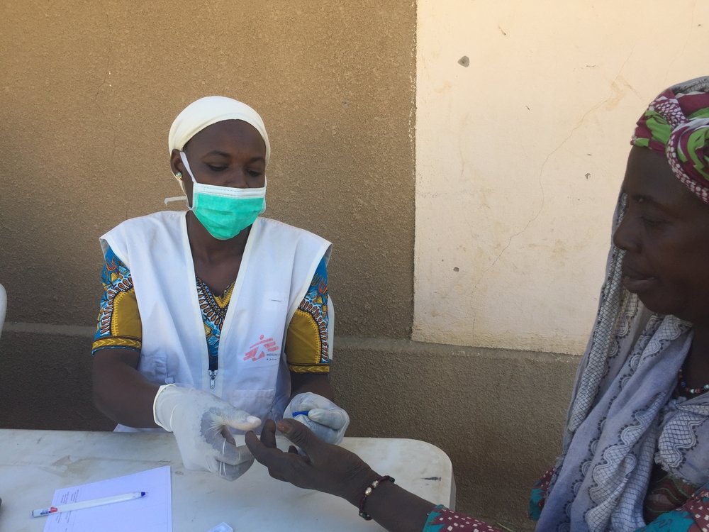 An MSF community health worker doing a rapid malaria test for a woman who has been displaced by conflict and is living on a site in Sokolo, Niono, in the centre of Mali.