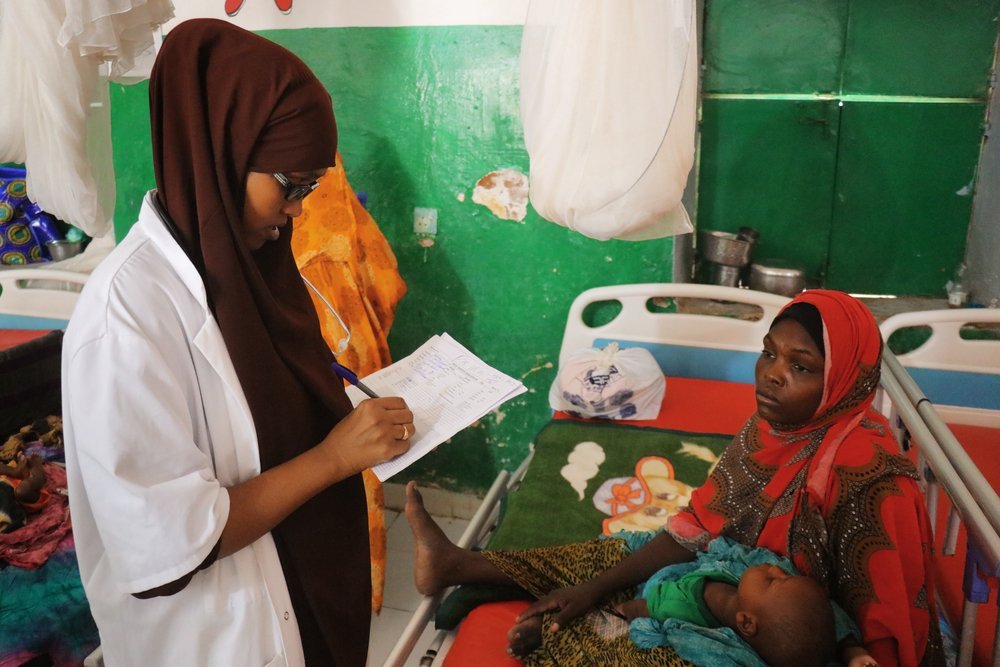 Kawsar Ibrahim Osman, a 25-year-old mother, holds her eight-month-old son Bilal, as he is checked by nurse Fartun Said Abdalla in the inpatient therapeutic feeding centre at the Mudug Regional Hospital in Galkayo city, Somalia.