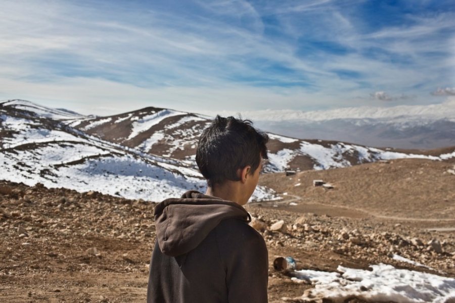 A young Syrian refugee looks out over the snow-swept mountains outside a half-built mosque serving as his family&#039;s home in Lebanon&#039;s Bekaa Valley, January 23, 2013.  The family chose to live in the mountain-top mosque for fear of spies in town. 
