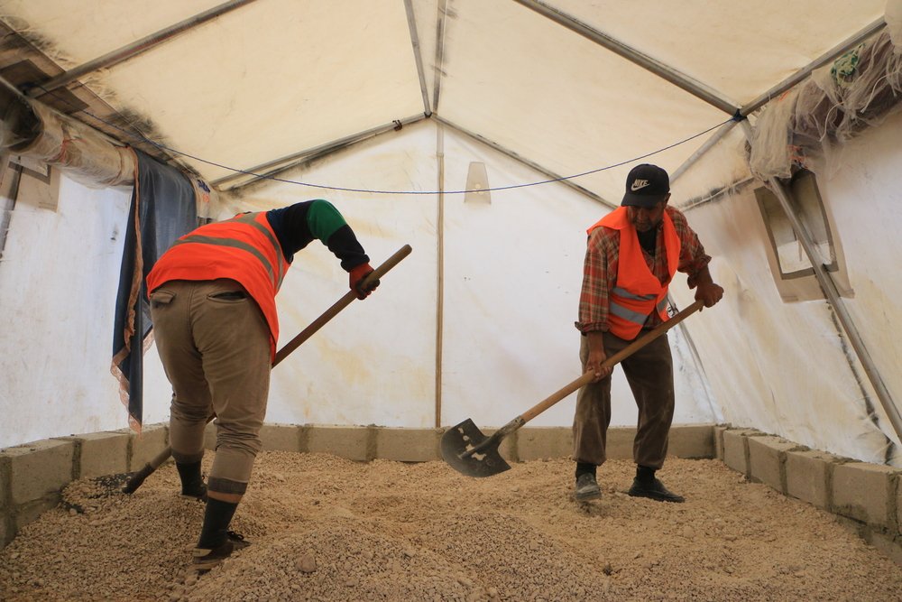 MSF logistics team are raising the floors of tents in a displaced camp in northwest Syria.
