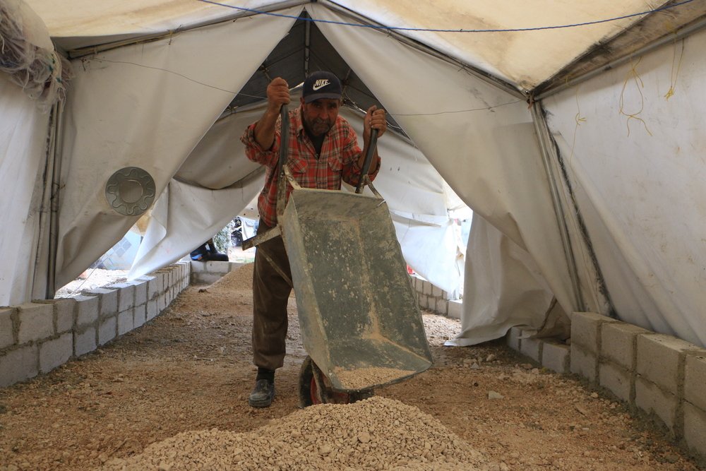 MSF logistics staff are preparing to raise the floors of tents in a displaced camp in northwest Syria.