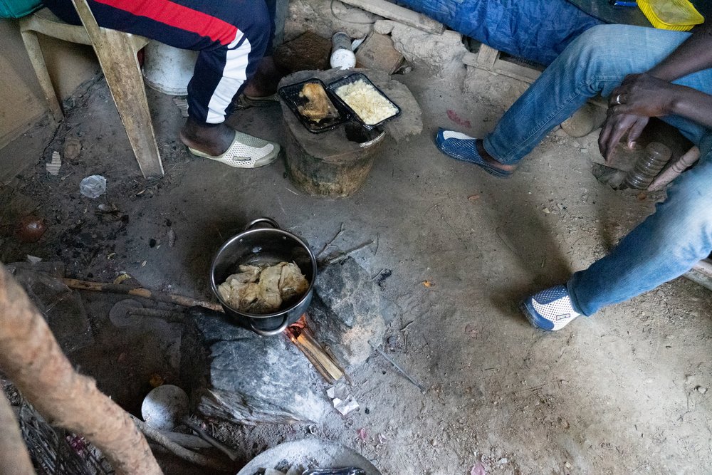 Men sitting around a bonfire where they re-cook the food which is distributed in the reception center of Vathy.