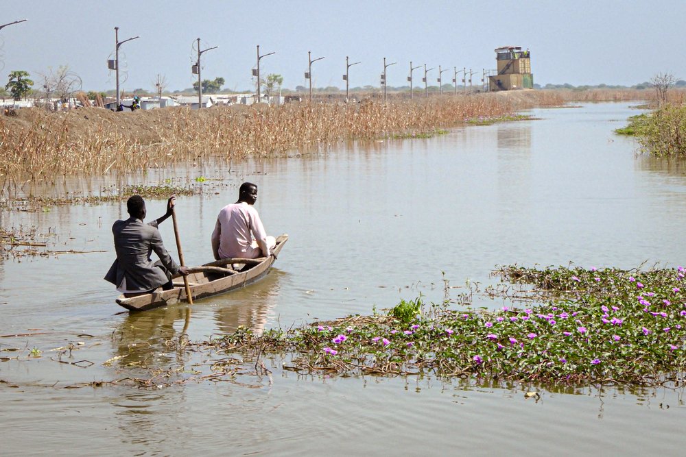 Two men use a canoe to navigate through floodwaters on the outskirts of Bentiu internally displaced persons camp.