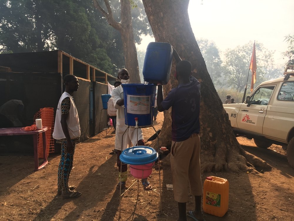 The MSF emergency team fills buckets with water for patients to wash their hands before their consultation. The mobile clinic has been set up in front of the hospital, next to a site for displaced persons who fled post-election violence in CAR. 