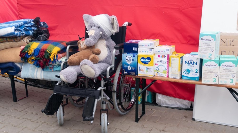 A stuffed toy sits in a wheelchair at Medyka border crossing next to many other donated items. (March, 2022).