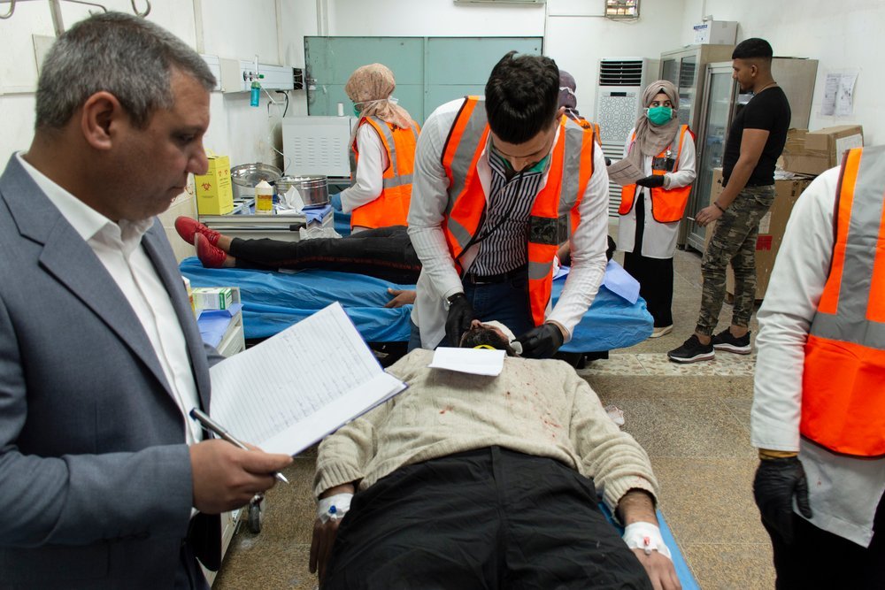 An observer looks on as an MSF nurse examines a patient during a training simulation exercise at Al-Hakim General Hospital in Najaf. Iraq, February 2020.