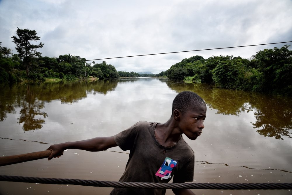 A ferry worker transports an MSF vehicle across the Sewa river in Kenema district, eastern Sierra Leone. People, cars and goods are transported across this ferry, using a wooden stick that pulls an iron rope.