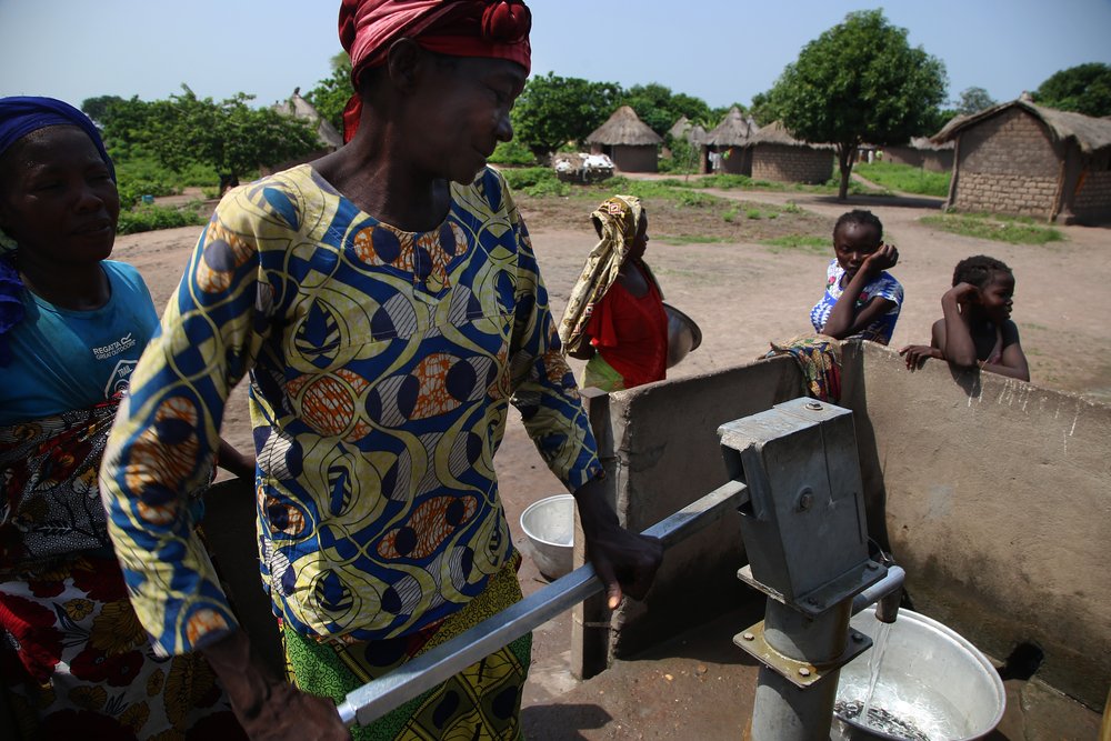 A woman pumps water into a bucket at a water point of site B for displaced people in Kabo, a town in northern Central African Republic.