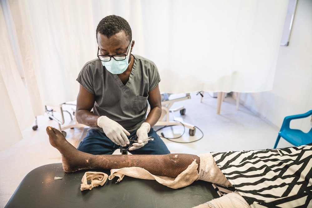 MSF staff cleaning a skin graft for a patient who suffered a severe burn on her leg. (October 1st. 2021).