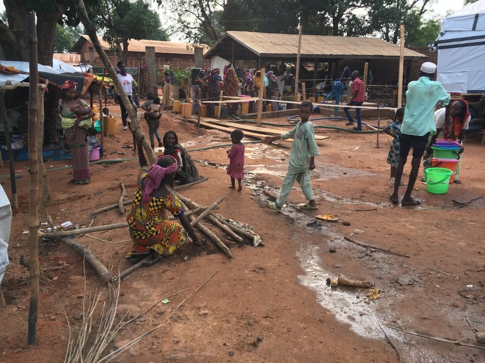 Displaced people fill containers at a water point in a mosque compound in Bambari town, Central African Republic, where several thousand people sought refuge following the destruction of Elevage camp in early June. 14 June 2021.