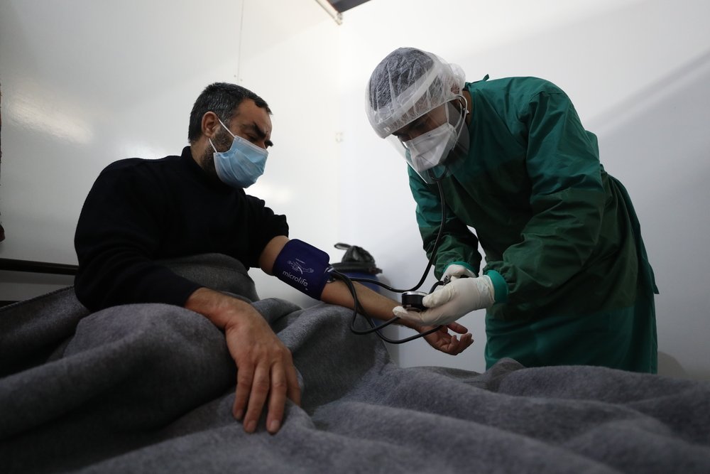 MSF nurse checking a patient’s blood pressure level inside the ward for patients with confirmed COVID-19. Inside MSF’s isolation and treatment centre in northwest Syria. December 2020.
