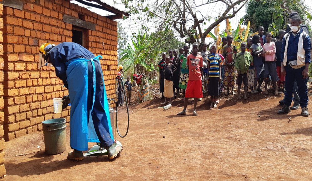 Curious children are gathering around a sprayer who is getting ready to treat a house against mosquitoes during the 2019 indoor residual spraying campaign in Kinyinya health district.
