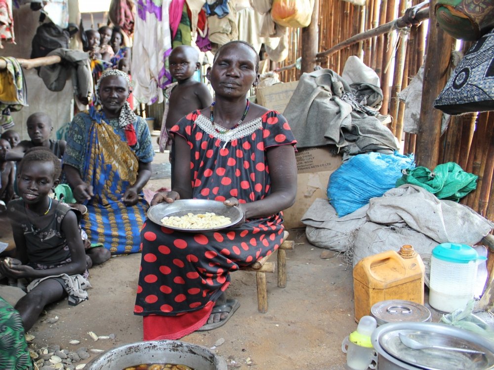 45-year old Nyachuol* prepares a meal of forest fruits for her children. Her husband was killed during fighting, and four other children remain in South Sudan. She does not know where they are.