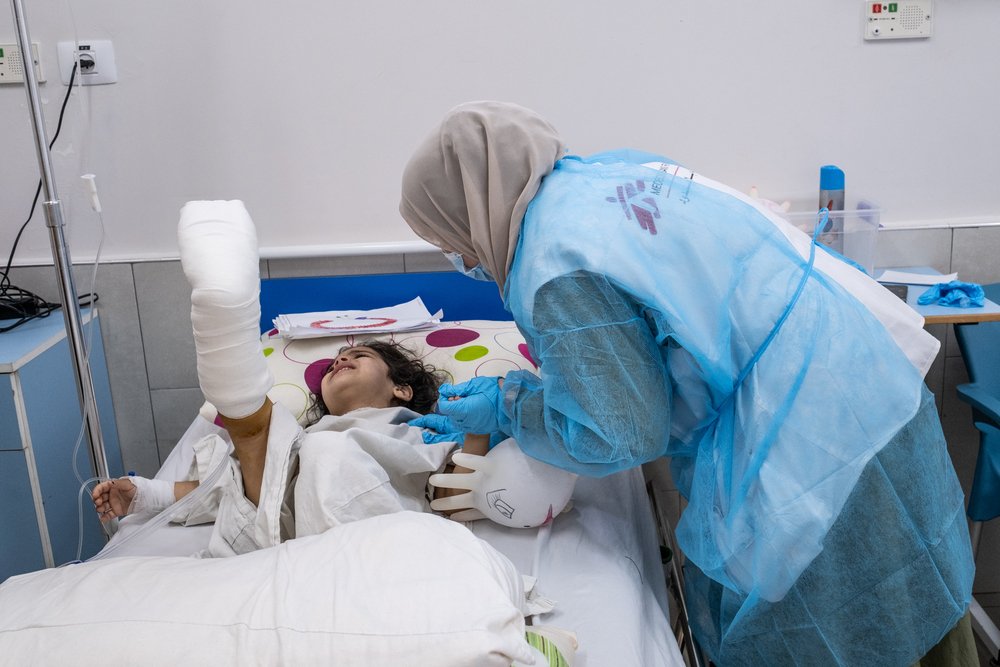 A nurse comforts four-year-old Hala as she recovers from reconstructive surgery on her foot. The surgery was performed by the MSF limb reconstruction unit.