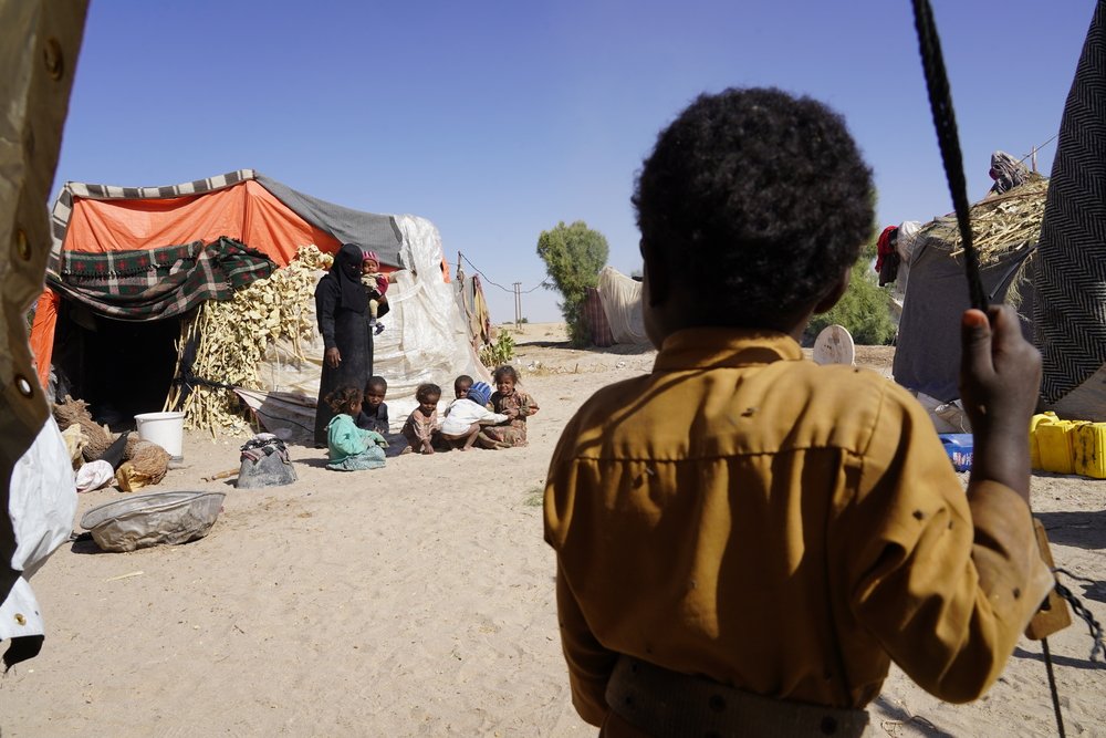 Children sit outside their tent in Al-Khuseif camp for internally displaced people in Marib. (December, 2021).