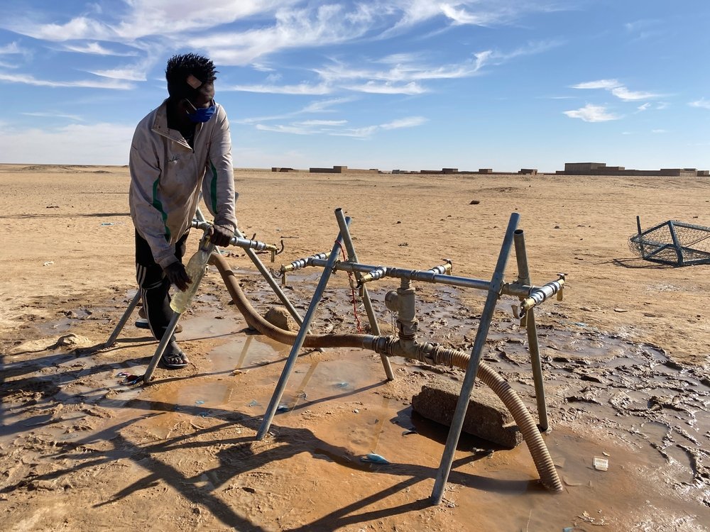 A young man fills a water bottle at a pump installed by MSF in Assamaka. Since 2018, MSF teams have been helping migrants who have become lost in the desert in Niger.