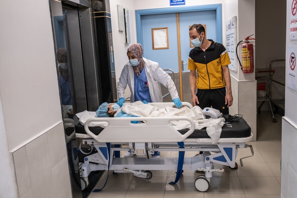 Mohammed Aboud, a father of five, follows his four-year-old daughter Hala as she is transferred to her hospital room at Al-Awda hospital from the limb reconstruction unit operating theatre.