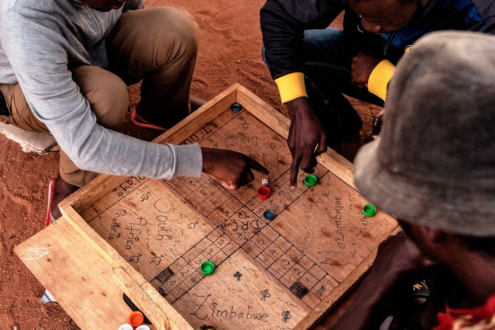 Men staying at a shelter for refugees in Musina, South Africa play a game of &quot;Ludo&quot; on a board with the names of the various countries some of the migrants who have stayed at the camp come from.