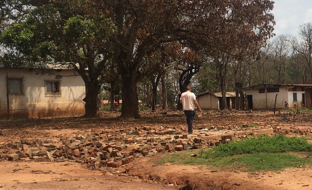 An MSF staff member walks through the ruins of an MSF health post which provided malaria treatment at Elevage camp for displaced people, on the outskirts of Bambari, destroyed in early June 2021. 15 June 2021.