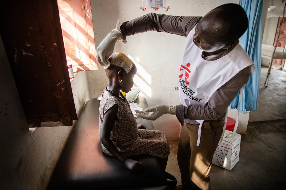 An MSF staff member examines the head injury of a young girl at a hospital in Ulang.  Northeast South Sudan, April 2019. 