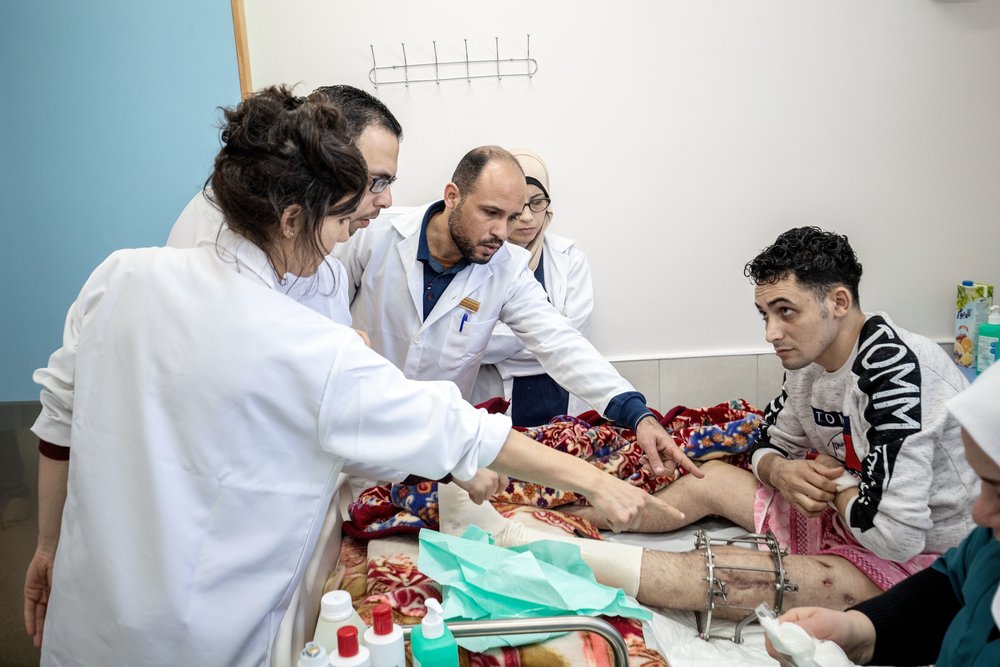 An MSF medical team discusses the condition of Hussni Alatar, wounded in his right leg during the Great March of Return protest, February 2020, Al Awda Hospital, Jabalia, northern Gaza.