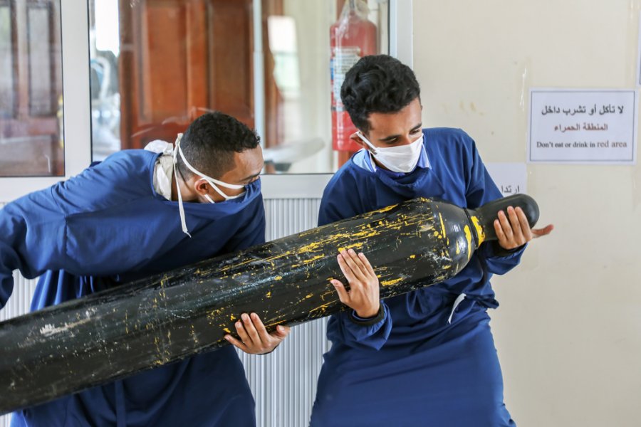 Two workers at the COVID-19 centre in Al-Sahul, Yemen, which is supported by MSF, carry a heavy oxygen bottle to the ICU. A patient with COVID-19 may need up to six of these bottles per day.