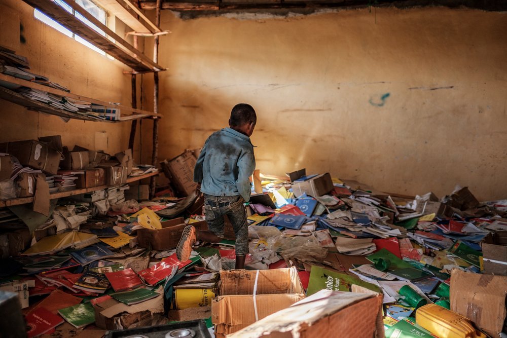 A child walks among books in the library of a former elementary school that was damaged during the fighting that broke out in Ethiopia&#039;s Tigray region, in the village of Bisober, on December 9, 2020. 