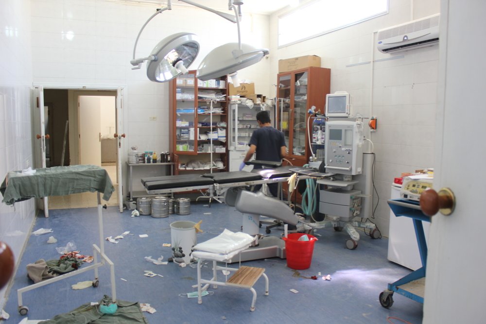 Operating room following a surgery with man in scrubs searching in a cabinet of medicine