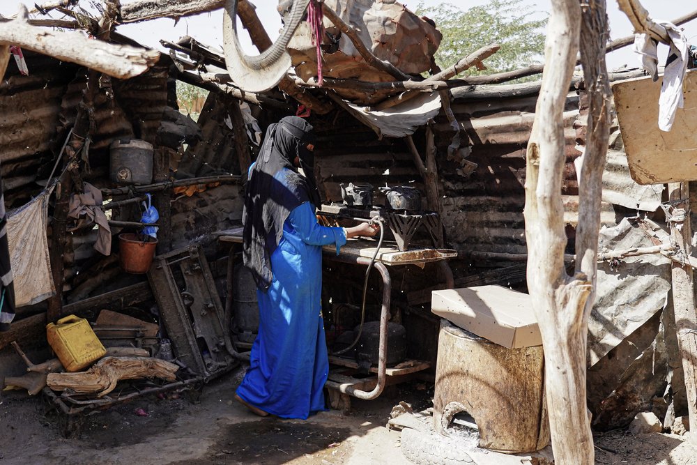 A woman preparing food in a self-built makeshift kitchen next to her tent in Al-Hussun camp for internally displaced people in Marib, Yemen. (Decemberm, 2021).