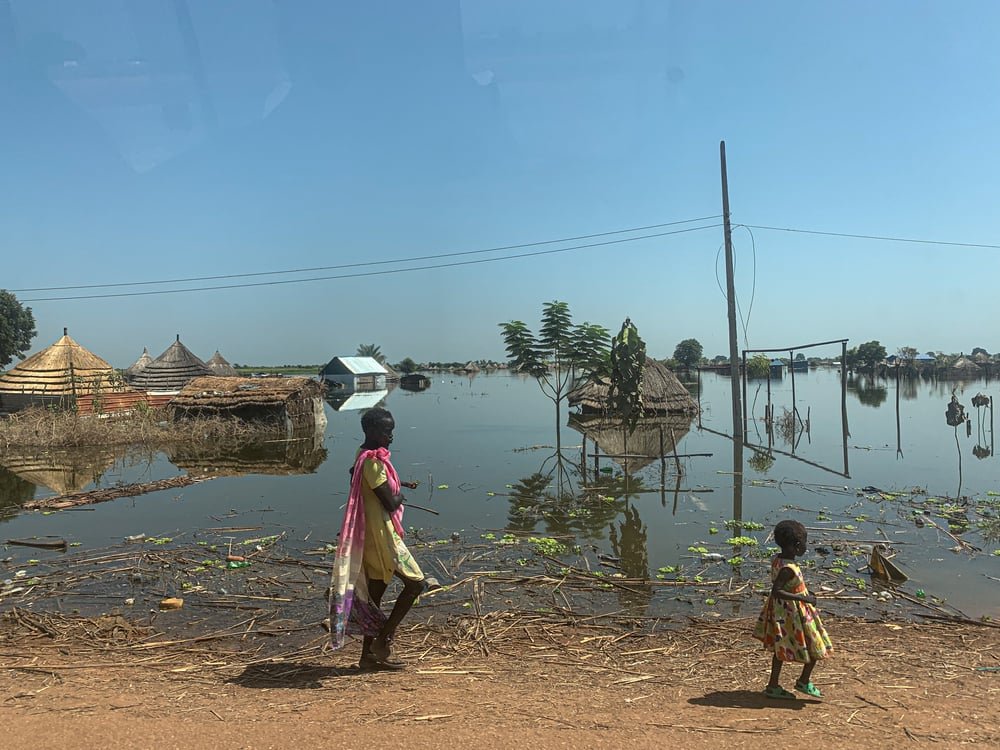 A women and her small child walk through flooded Bentiu town, Unity state.