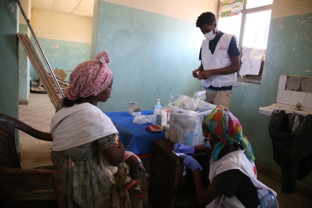 An MSF staff member provides medication to a woman and her child after a medical consultation during a mobile clinic in the village of Adiftaw, in the northern Ethiopian region of Tigray.