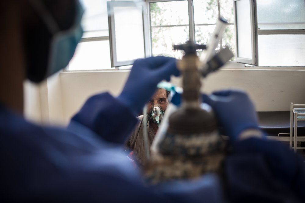 A patient receives care in the COVID-19 ward of Raqqa National Hospital, in northeast Syria. In the foreground, a nurse regulates the oxygen supply. (June, 2021).