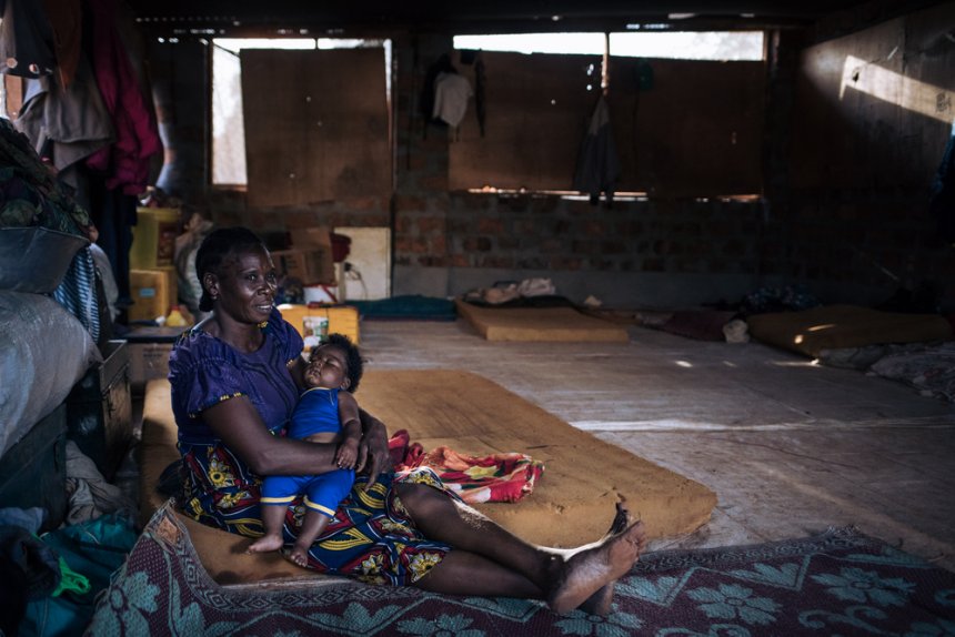 Béatrice, 43 years old, is sitting in an empty building of the Bangassou hospital with one of her grandchildren. 