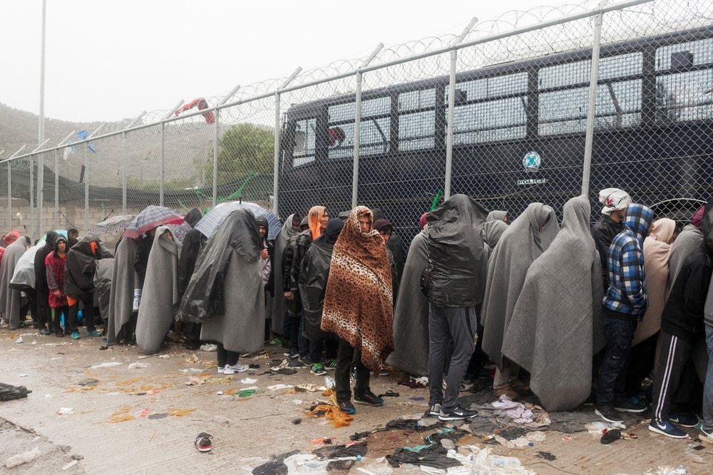 Refugees look through a fence during a rain storm as they wait to be registred at the Moria Reception Centre on Lesbos island.