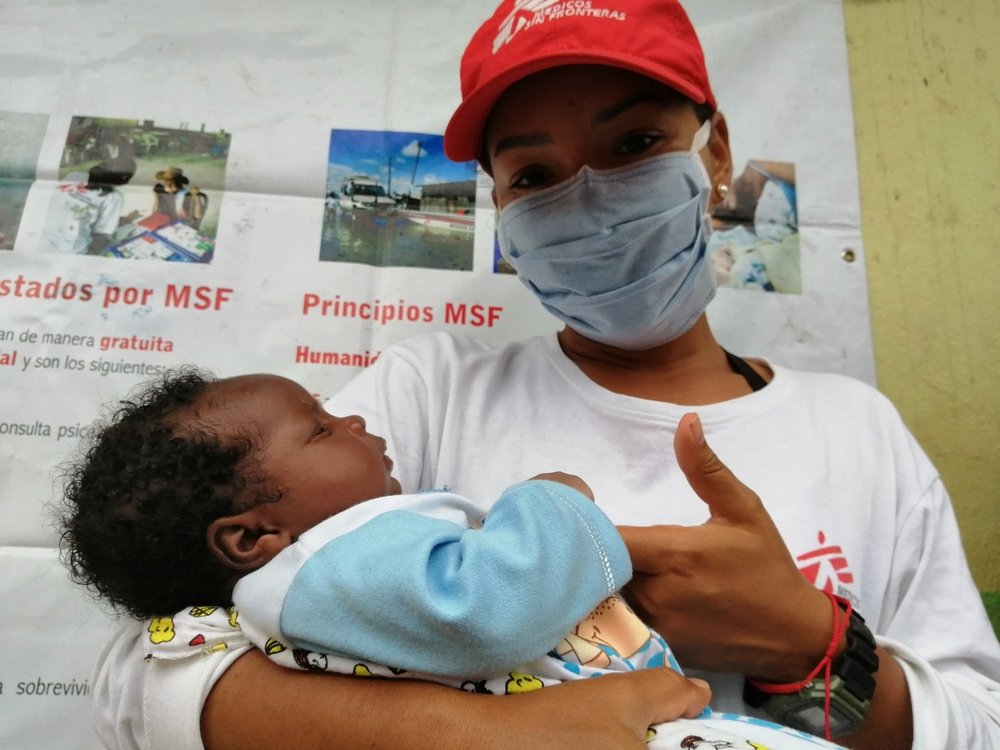 MSF psychologist cares for a baby while its mother undergoes a contraception implant.