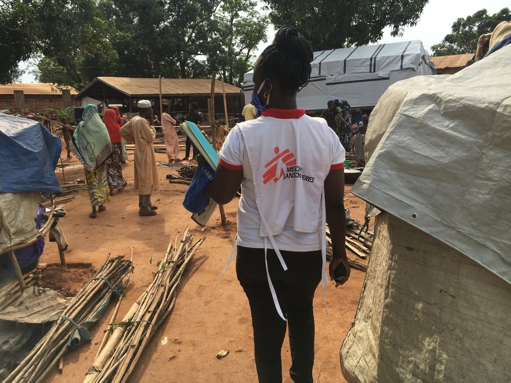 An MSF staff member stands near displaced people in the compound of a mosque in Bambari town, Central African Republic, where thousands of people sought refuge after Elevage camp was destroyed in early June. 14 June 2021.