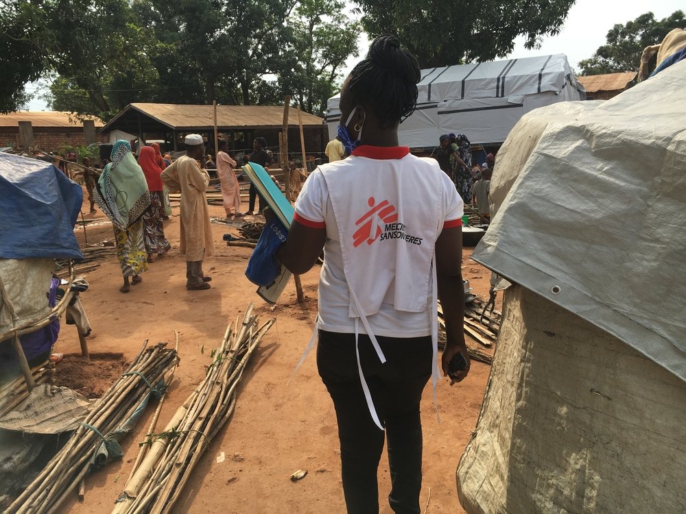 An MSF staff member stands near displaced people in the compound of a mosque in Bambari town, Central African Republic, where thousands of people sought refuge after Elevage camp was destroyed in early June. 14 June 2021.