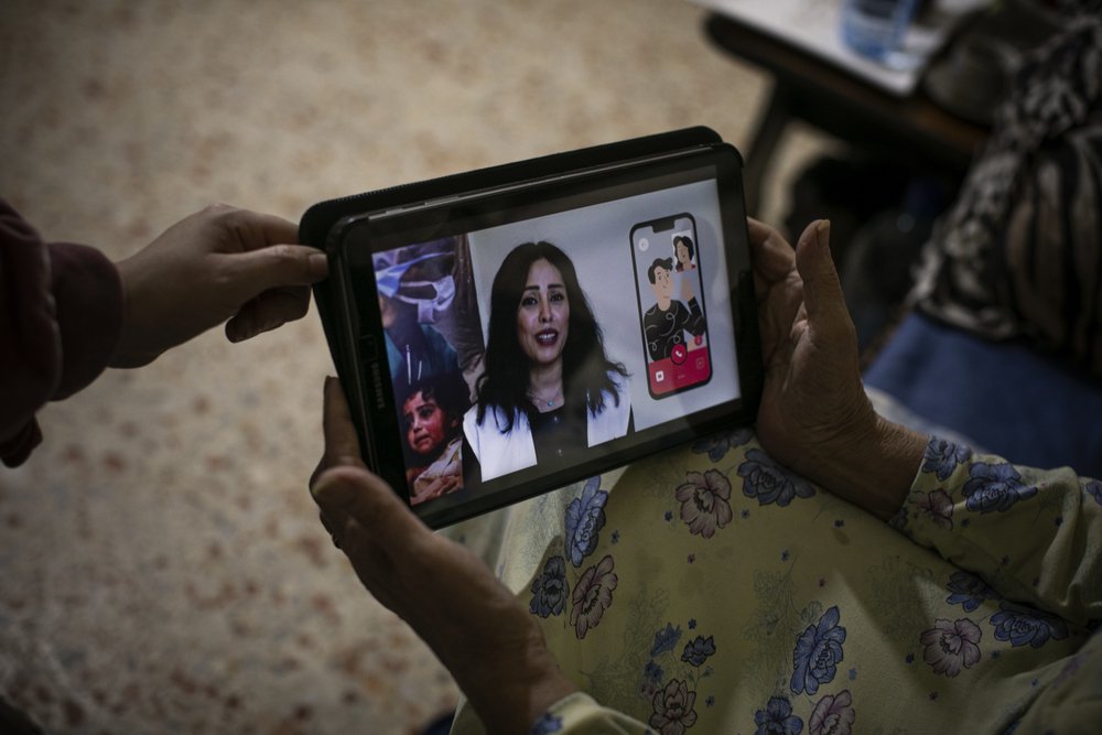 Hala, MSF nurse, is showing a health promotion video on a tablet to Mousera during a regular check-up visit. 