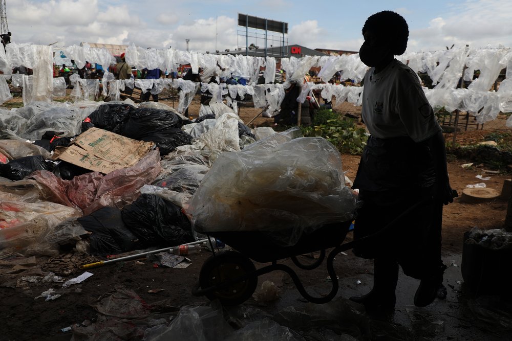 A woman wheels a collection of waste through the Mbare solid waste recycling depot. (April, 2022).