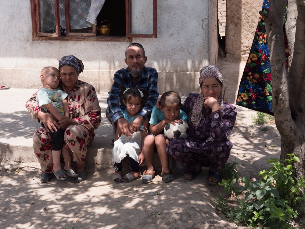 Surayo (29) with her son Zainidin (8), daughter Bibisoleha (6), her parents and her nephew in front of their house in near Tursonzoda in western Tajikistan. (July, 2021).