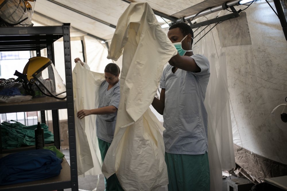 Melissa How and Alain Nizigiyimana, both MSF nurses, in the dressing area getting ready with protective equipment before entering into the patients area.