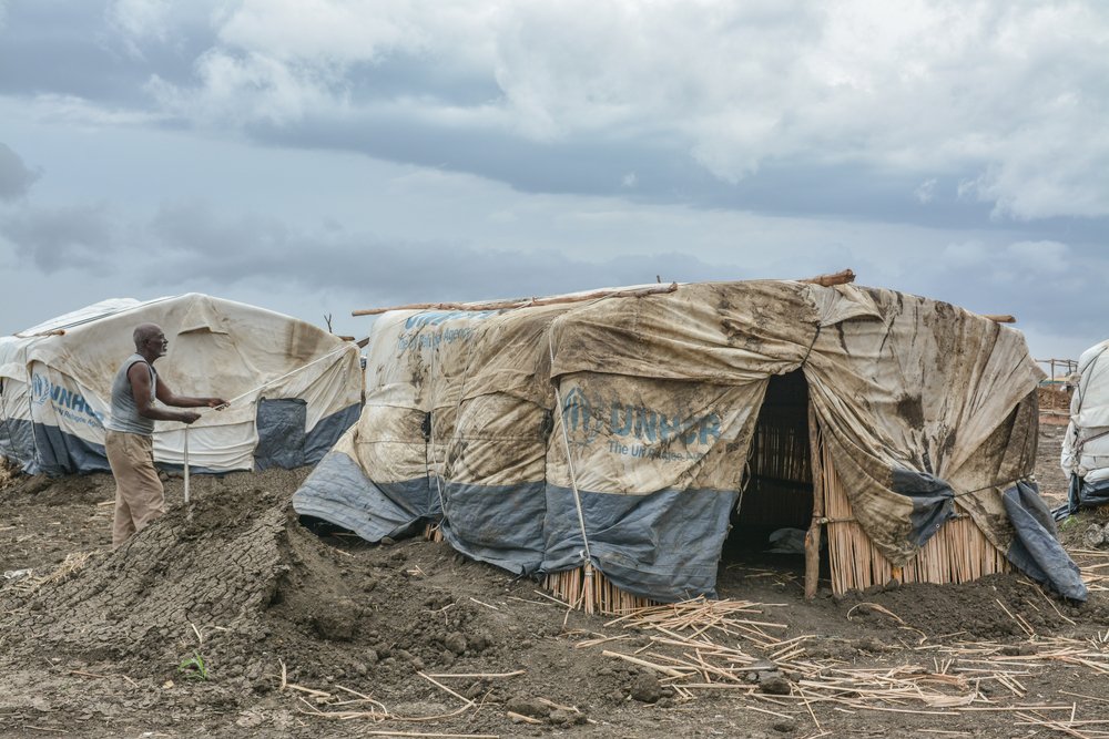A man in Al-Tanideba camp works to reinforce his shelter. Weeks of heavy rain and wind have destroyed many refugee shelters across the camp, contaminating water and food supplies.