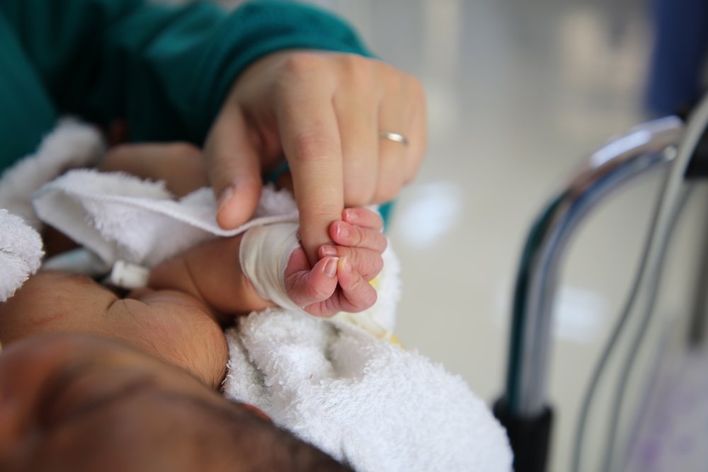 A newborn baby grips the finger of nurse, Réne Stone, who is supervising the child’s nursing care at the special care baby unit supported by MSF at Al-Jamhouri hospital in Taiz City, Yemen.